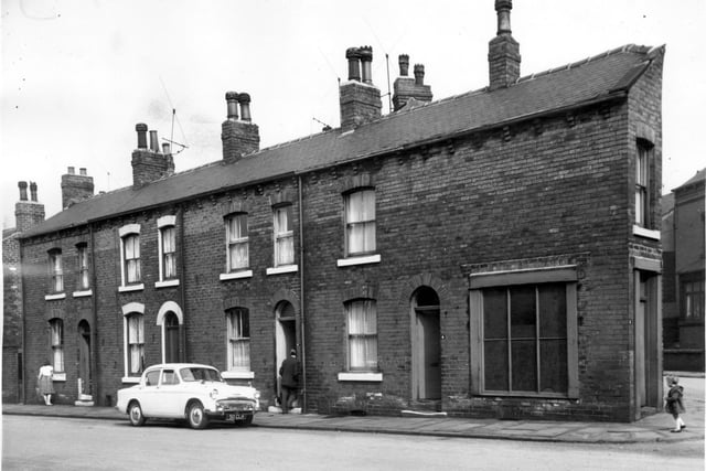 A woman is washing her window sills on Anchor Road. The junction of Anchor Road and Anchor Terrace formed a wedge-shape, number 2 Anchor Road is here, a child is in front of the property. Pictured in April 1964.
