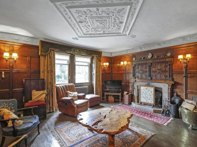 The living room with original wood flooring and panelled walls, has a feature stone fireplace and hearth with open grate.