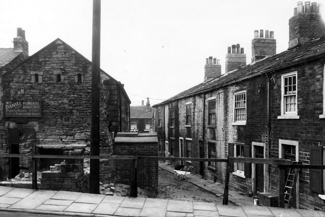This is looking from Delph Lane towards Peel Court. On the left is 2a Delph Lane, with a sign for William Daniel, joiner and funeral director. The houses on the right are back-to-back with 190 to 200 Woodhouse Street. Most of them have access to shop premises at the front. Pictured in September 1959.