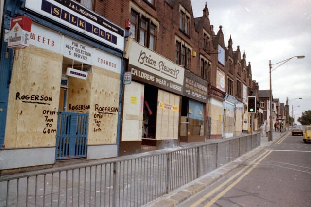 Harehills Road near the junction with Roundhay Road in July 1981. Shops visible include J. & L. Rogerson, newsagents, sweets & tobacco, Brian Stewart's children's wear and lingerie and M.C. & J. Fashions. All are boarded up due to riots which had been taking place in the area during a time of nationwide unrest. Police cars had been overturned in Chapeltown and this had become a no-go area, though some of the shops were trying to remain open as usual