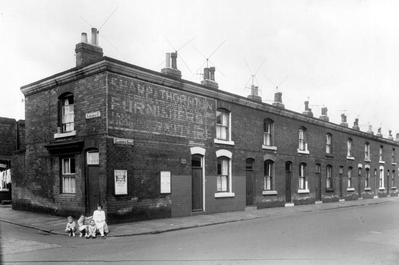 Clarence Road at the junction with Hazelhead Street in August 1961. A group of four children sit on the pavement outside no 2 Hazelhead Street on the corner. A board on the wall advertises 'Seacroft Show and Gala.'