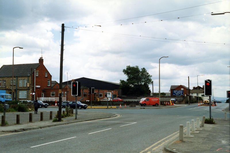 July 1990 and pictured is Bruntcliffe Lane looking onto the junction with Bruntcliffe Road to the left, Howden Clough Road ahead and Wakefield Road to the right. On the left is the Bruntcliffe Working Men's Club; behind this, are the works of Crabtree & Astin Ltd, joinery manufacturers. The white building on the right is the Shoulder of Mutton Inn.