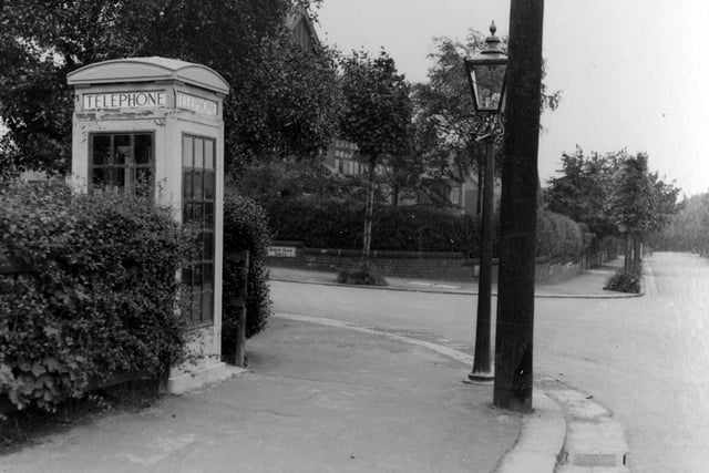 This view shows Lidgett Park Road on the right by the junction with North Park Grove in June 1938. A telephone kiosk can be seen on the corner, along with a street lamp and telegraph pole.