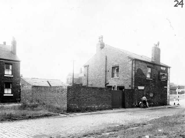 Barleycorn Street onto the back of the Barleycorn Hotel which is located on Whitehall Road. Towards the right a man stands next to a motorised bicycle. Pictured in March 1965.