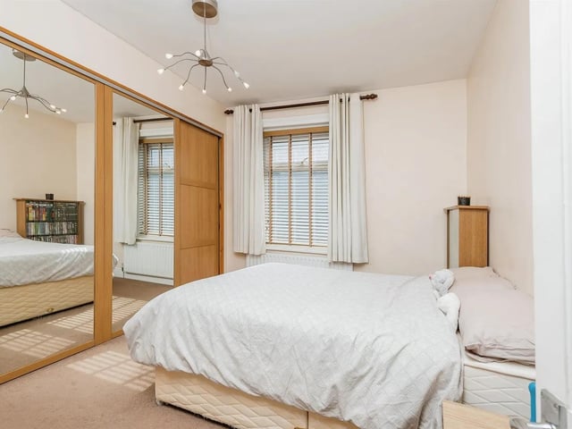 This spacious master bedroom has built-in mirrored wardrobes and a cast iron feature fireplace.