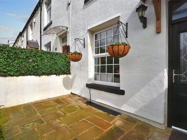 To the front of the property is a paved garden area with planted shrubs.