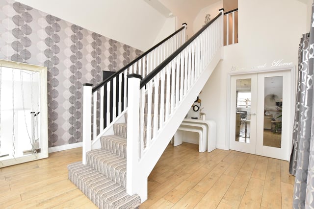 An impressive and spacious entrance hallway with a large window, fitted storage and a central staircase rising to the first-floor accommodation.