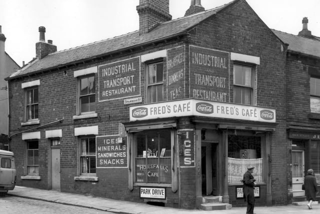 A man stands outside Fred's Cafe on Tong Road while a lady walks past Jean's Hairdressers, just seen on the right edge. Pictured in May 1965.