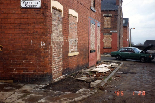 A corner of Fearnley Street prior to demolition. Windows and doors have been bricked up and the pavement has been dug up. The next row of houses is Gledhow Street. These two streets were part of series of long streets which ran between Hall Lane and Tong Road. Pictured in January 1985.