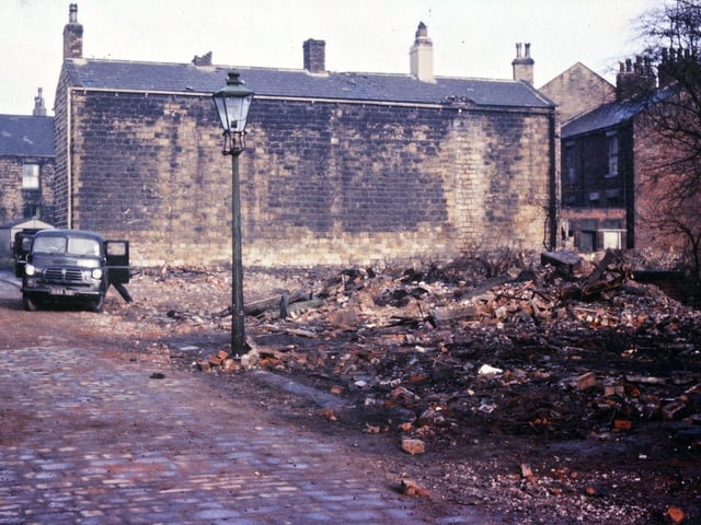 Slum clearance on Jackson Lane, looking towards Victoria Road. The site of the former fish and chip shop was by the old gas lamp. The houses on the right have their front on Church Street. Many old blocks of terraced houses in Morley were built like the one in this image - with no windows or doors in three of the four sides of the block. Pictured in February 1962.