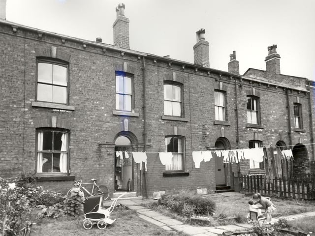 Three back-to-back properties on Parsonage View. A bicycle and a pushchair can be seen outside number 19 while a girl plays with her own pushchair further along the path. These gardens backed onto allotments with passageways such as the one on the right edge giving access to Main Street. Pictured in August 1966.