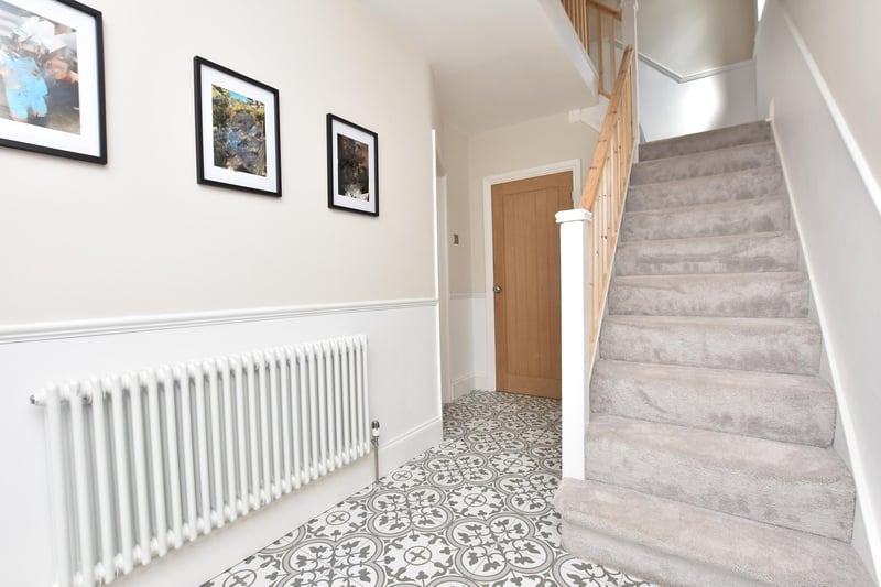 The entrance hallway features tiled flooring, dado rail, column radiator and staircase to the first floor