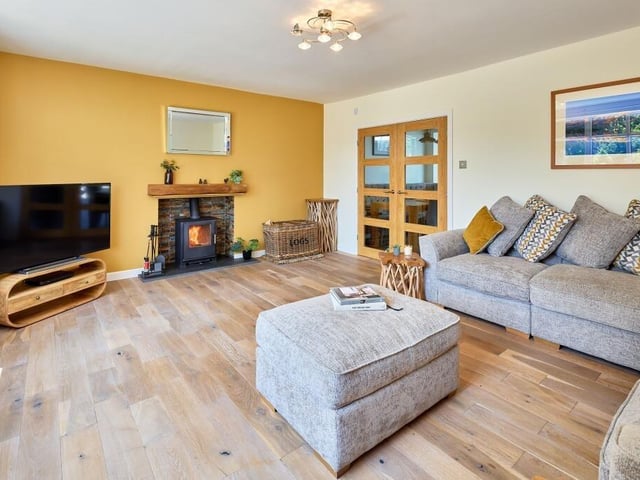 The lounge has an engineered timber flooring and chic statement column radiators, as well as a cosy log burner beneath an oak lintel.