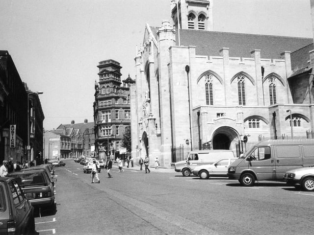 Cookridge Street with St. Anne's Cathedral prominent at the junction with St. Ann Street. Beyond the cathedral the Leonardo Building can be seen at the corner with Great George Street while on the left of the photo is a branch of Austick's bookshops.