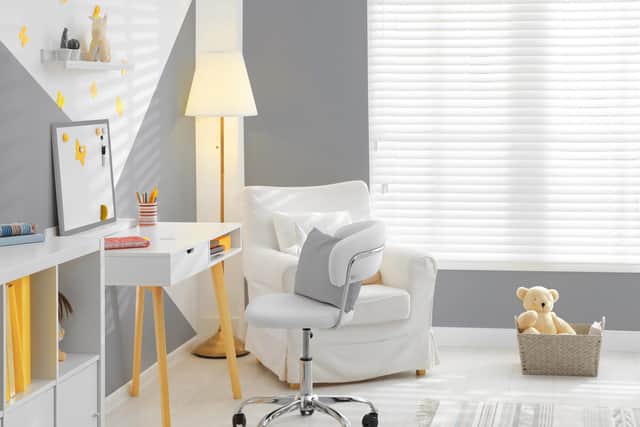 A light and bright child's room with window blinds, a desk and chair, and comfortable seating.