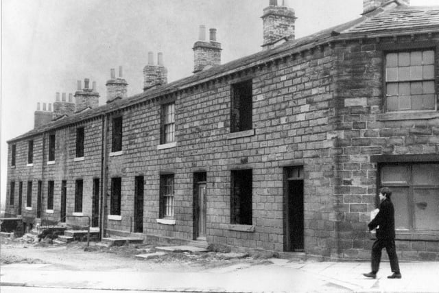 Derelict houses on Gelderd Road in Gildersome pictured in May 1967. House second from the right still has curtains to the windows and could still be occupied. A boy is walking along the road in the foreground.