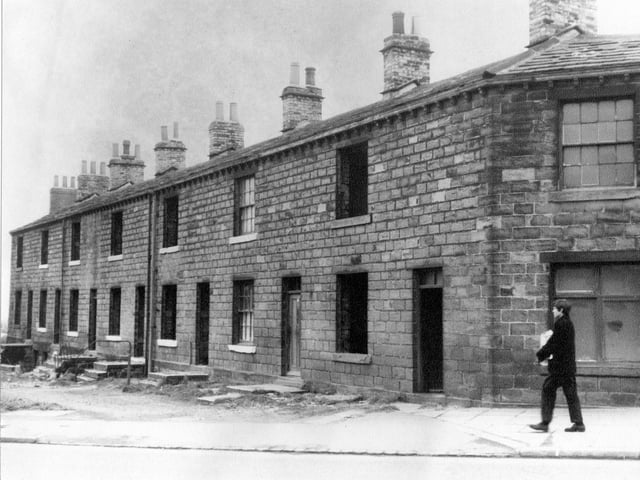 Derelict houses on Gelderd Road in Gildersome pictured in May 1967. House second from the right still has curtains to the windows and could still be occupied. A boy is walking along the road in the foreground.