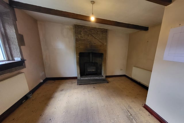 In the sitting room, the full height fireplace is a dominant feature, with its large hearth and wood burning stove.