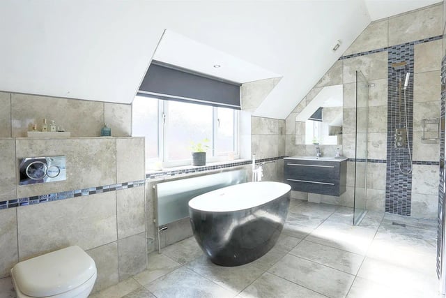 This luxury en-suite is fitted with a modern suite comprising; freestanding bath, wet room-style shower, large vanity unit with a hand wash basin inset.