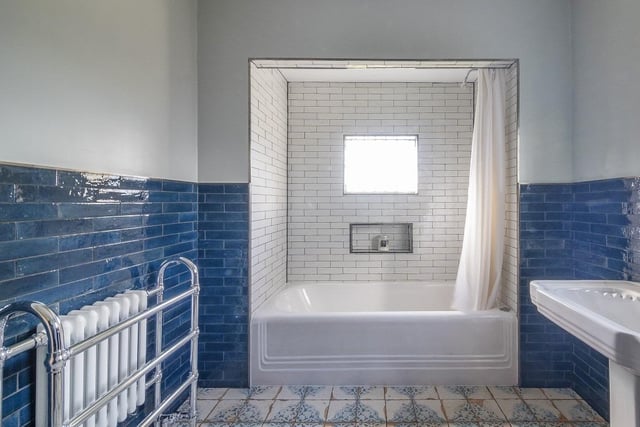 The main house bathroom has been newly updated with an opulent three-piece suite having a tiled surround with the original enamel bath, sink and hardware.