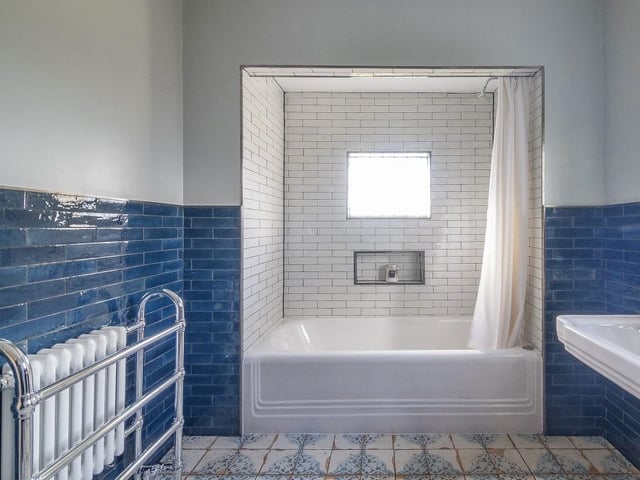 The main house bathroom has been newly updated with an opulent three-piece suite having a tiled surround with the original enamel bath, sink and hardware.