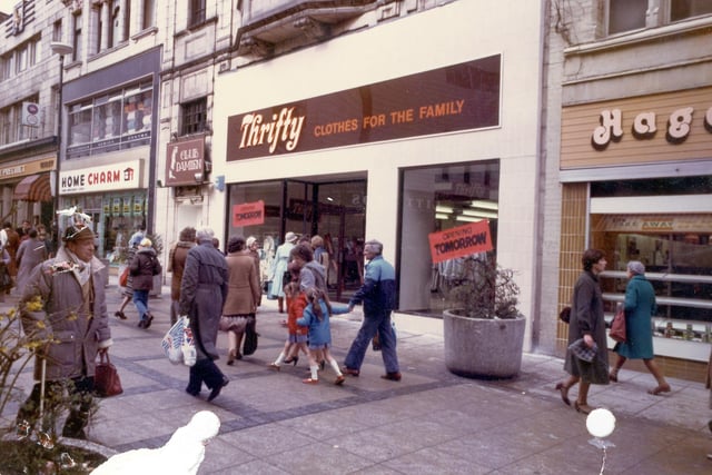 Kirkgate in April 1983. The Precinct public house is on the left  followed by Home Charm. Next to this is the entrance to Club Damien night club, which occupies the floor above. Thrifty, Clothes for the Family, due to be opened on the following day. On the right is Hagenbach bakers at no.18. The pedestrianised street in front is busy with shoppers.
