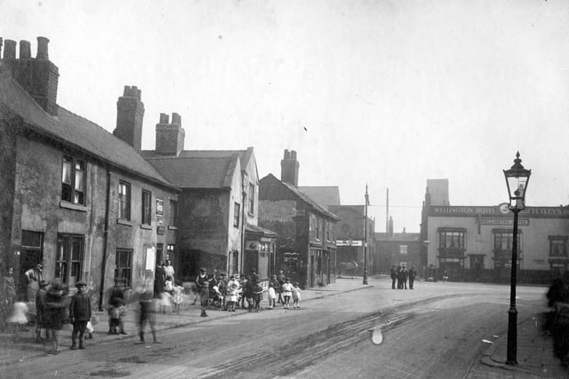 Church Street junction with Low Road showing Wellington Hotel in August 1929. There is a group of men in centre of the road and a gathering of children on the path and road outside properties.