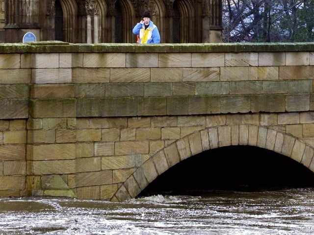 An onlooker watches as the swollen River Calder runs under Chantry Bridge in November 2000.
