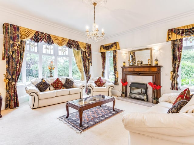 Another spacious and elegant room with central fireplace and large windows with garden views.