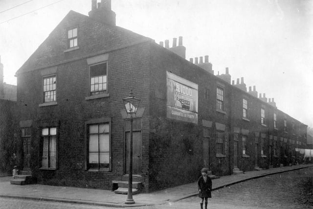 Looking from Low Road down Society Street, a row of two storey terrace houses. An advertisement for Sunlight Soap is on the wall, gas lamp on pavement. The Street to the left is Humane Street.