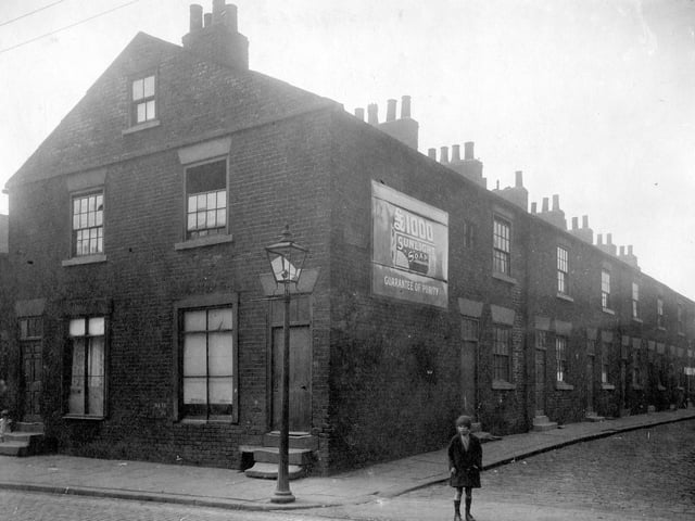 Looking from Low Road down Society Street, a row of two storey terrace houses. An advertisement for Sunlight Soap is on the wall, gas lamp on pavement. The Street to the left is Humane Street.