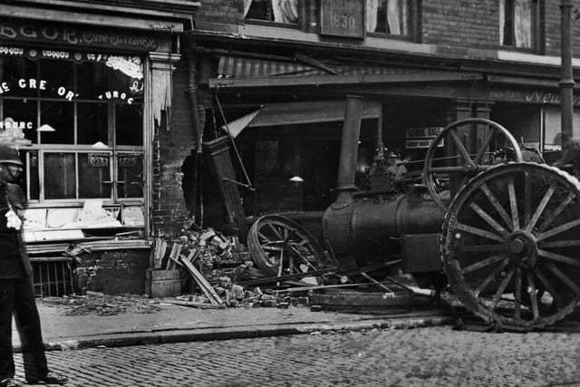 The aftermath of an accident on Woodhouse Lane in July 1911 after a nine-tonne steam traction engine ran out of control and crashed into a sadler's shop. It also wrecked a confectioner's shop next door. A report in the Leeds Mercury stated the engine belonged to Messrs Arnold & Sons of Doncaster, and was on its' way to Knostrop Sewage Works, with driver Albert Johnson and William Starkless steering, when a clutch pin came out, causing the engine to speed rapidly downhill and break the steering chain. Both wheels came off in the accident, as seen in the photograph. A policeman can be seen on the left viewing the wreckage.