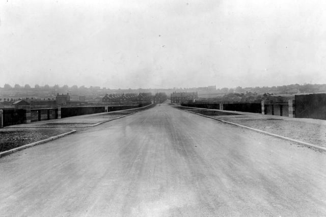 The newly built Low Fields Road linking Elland Road and Gelderd Road. Houses in the distance. Pedestrian pathways to the left and right of the road whilst building work continues to the right. Pictured in  June 1923.