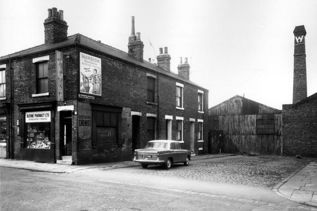 Blooms Pharmacy Ltd., the dispensing chemist, on Temple View Road in July 1963.  A sign on the side window offers 24 hour developing and printing of photographs. On the right of the image are numbers 2 to 4 Berking Terrace, two back-to-back terraced houses with a car, reg: 271 FNW parked outside.