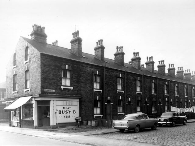Barrack Street at the junction with  Wilmington Grove in October 1960.  In focus are  L. Henshaw, grocers shop and a branch of the 'Busy B' butchers shops. The shop delivery bike is parked outside.