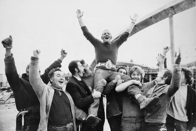 Bradford battler Richard Dunn, who beat Bunny Johnson on points over 15 rounds to win British and Commonwealth Heavyweight Championship, was back at work in October 1975  wearing his new Lonsdale belt. He is pictured being cheered by workmates at the Odsal Sport Complex in Bradford where he is employed as a scaffolder. "This is one of the greatest days of my life. It is just fantastic," he said.