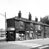 Part of Dewsbury Road in view, on the left is the junction with Jack Lane. The shop on the corner is a newsagents, number 41 Dewsbury Road, business of Emily Tillotson. Moving right, 43 is a watch and clock repair shop next, 45 is a shop then 47, 49 are boarded up. At 51 is the Cricketers Arms public house, serving Ind. Coope Beer. Numbering continues in sequence to the right ending at the corner with the blind down is 63. Matthews grocers. In the top right corner a clock and Tetley's sign are outside the Parkfield Hotel, another public house. Pictured in May 1963.