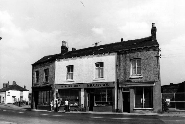 A view of Main Street in East Ardsley in July 1975. Businesses include Archer's 'the paper shop' in the centre, outside which a group of children are standing. On the far left is number 30 Main Street.