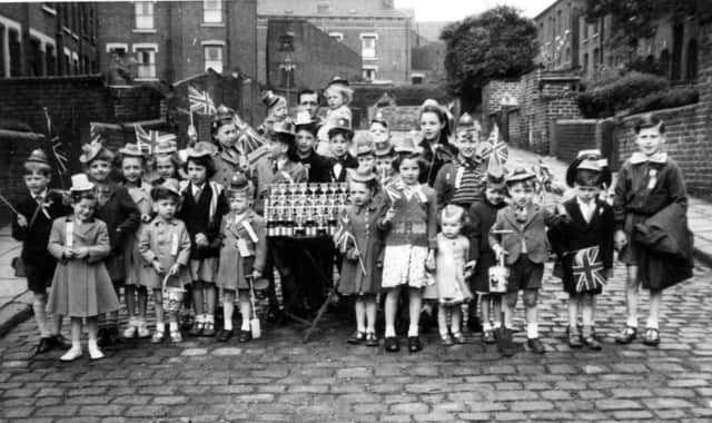 A group photograph showing the children of Greenmount Place and Greenmount Street in Beeston with Coronation silver cups, before they set off on an outing to Redcar in celebration of Coronation day.