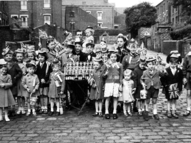 A group photograph showing the children of Greenmount Place and Greenmount Street in Beeston with Coronation silver cups, before they set off on an outing to Redcar in celebration of Coronation day.