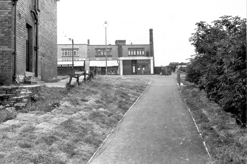 A view along a footpath, known as Burnley Walk, linking Dewsbury Road and Allenby Road. Kirby fish and chip shop, Boland's drapers and and Hobson's confectioners visible. Pictured in June 1956.
