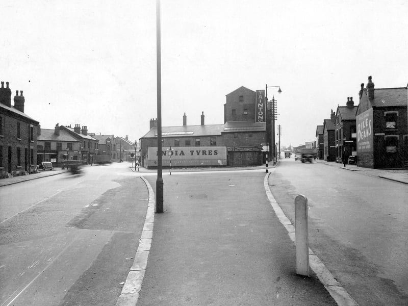 Gelderd Road at the junction with Whitehall Road in September 1950. 'Tainton Ltd', can be seen in the centre. Adverts for 'Bile Beans', 'India Tyres', 'Greys Cigarettes', visible. Traffic on the roads.