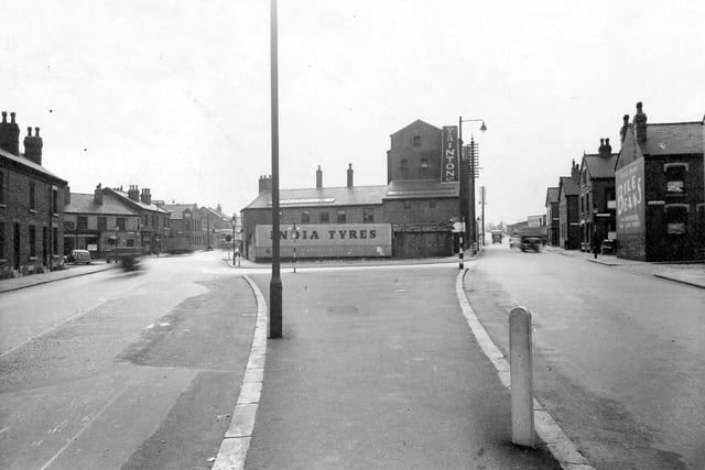 Gelderd Road at the junction with Whitehall Road in September 1950. 'Tainton Ltd', can be seen in the centre. Adverts for 'Bile Beans', 'India Tyres', 'Greys Cigarettes', visible. Traffic on the roads.