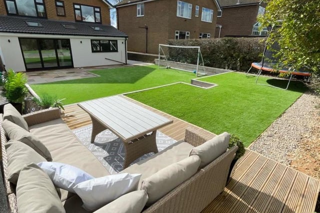 The tiered rear garden with decked seating area and artificial lawns.