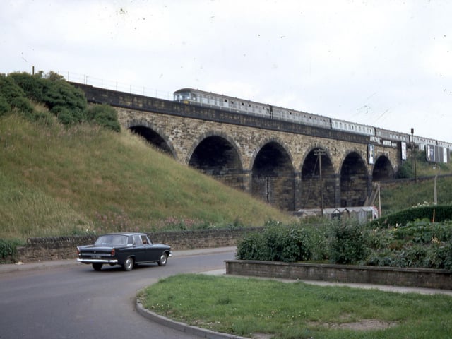 The railway viaduct from the bottom of Churwell Hill in July 1968. A diesel train crosses the six-arch viaduct while a car can be seen travelling on Old Road.