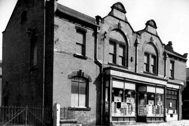 A view of the ornate frontage of the Leeds Industrial Co-operative Society Limited situated in Beatrice Place. Posters decorate the windows advertising saving to be made there eg. Wheatsheaf sliced peaches at 1s/ 6d - Save 4d. The butchers department or meat purveyors is situated adjacent to the grocery department on the right of the image. Pictured in April 1966.