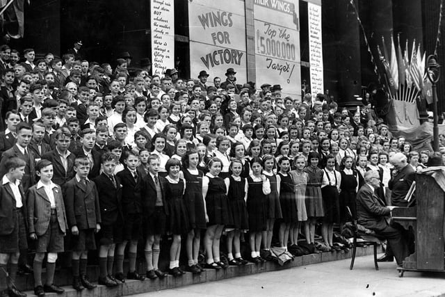 Massed choirs of Leeds school children on the steps of Leeds Town Hall in June 1943. Each day of the week long Wings For Victory campaign was given a special focus, this was Children's Day. In the background is the indicator board which was altered daily. A final total of £7.2 million was raised.
