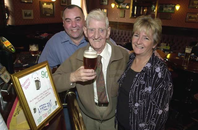 Regular Tommy Spurr stands in the same place as he has done for the last 72 years at the White Cross pub. He is pictured with landlord Colm and Sue O'Neill in October 2003.