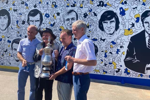 Paul Reaney, Paul Trevillion, Nicolas Dixon and Allan Clarke hold the FA Cup in front of the new mural.