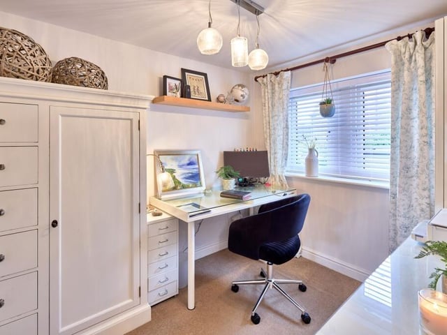 The home office incorporates storage solutions and a generous desk positioned beside the window.